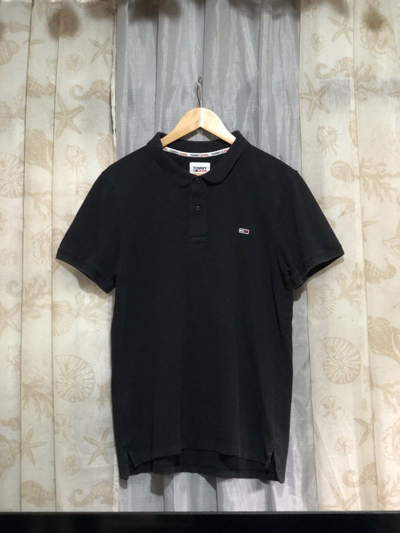 Tommy Jeans Black Polo Shirt (Category: Tshirts & Polo Shirts ) located in Calbayog City. Submitted by thriftme.bro (Listing ID 1469324470, Image 1). Description: Tommy Jeans black polo shirt with a classic collar and short sleeves. Features a two-button placket and branded inner collar tape. Small embroidered logo patch on the left chest. Ribbed cuffs and side hem slits. Made from soft cotton blend fabric. Clean look, goes with everything..