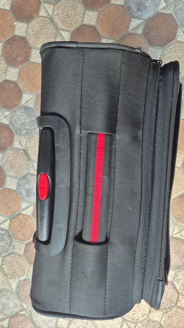 Travelite Softside Luggage (Category: Luggage) located in Imus. Submitted by erwin0000443 (Listing ID 1469239685, Image 2). Description: - Brand: Travelite - Color: Black with a red vertical stripe on the front pocket - Wheels: Smooth 360-degree double spinner wheels for effortless navigation - Security: Built in combination lock - Handles: Retractable telescopic top handle and comfortable side grab handle - Storage: Durable fabric construction f
