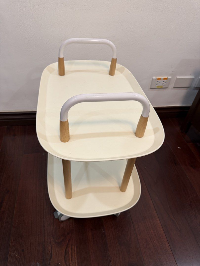 Two-Tier Rolling Utility Cart White and Wood (Category: Shelves, Cabinets & Racks) located in Makati City. Submitted by monkeykingo (Listing ID 1469257525, Image 2). Description: - Type: 2-Tier Rolling Utility Cart - Design: Modern white plastic trays with stylish wooden legs - Mobility: Features 4 caster wheels and dual top handles for easy steering - Condition: Clean surface, minimal wear - Usage: Versatile organizer for the kitchen, living roo