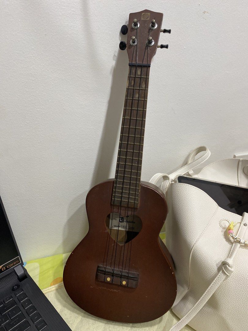 UKE BOX Ukulele Model UKE Love (Category: Musical Instruments) located in Manila. Submitted by vintageonlinee (Listing ID 1469233948, Image 2). Description: - Brand: UKE BOX (Model: UKE Love) - Color/Style: Brown acoustic ukulele with a unique heart-shaped soundhole - Build: Standard size, wooden fretboard with frets, and reliable tuning pegs - Strings: 4 standard nylon strings installed - Condition: Minor scuffs and marks from normal handling an