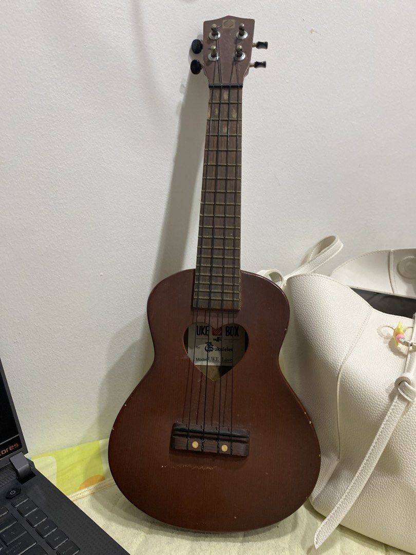 UKE BOX Ukulele Model UKE Love (Category: Musical Instruments) located in Manila. Submitted by vintageonlinee (Listing ID 1469233948, Image 1). Description: - Brand: UKE BOX (Model: UKE Love) - Color/Style: Brown acoustic ukulele with a unique heart-shaped soundhole - Build: Standard size, wooden fretboard with frets, and reliable tuning pegs - Strings: 4 standard nylon strings installed - Condition: Minor scuffs and marks from normal handling an