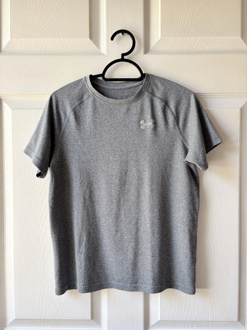 Under Armour Grey Athletic T-Shirt (Category: Babies & Kids Fashion) located in Liloan. Submitted by mrs.jboiser (Listing ID 1469202892, Image 1). Description: - Brand: Under Armour - Color: Grey with silver reflective logos (chest and back collar) - Style: Short sleeves, crew neck, raglan seams - Material: Lightweight, breathable athletic fabric - Condition: Excellent / Pre-loved.