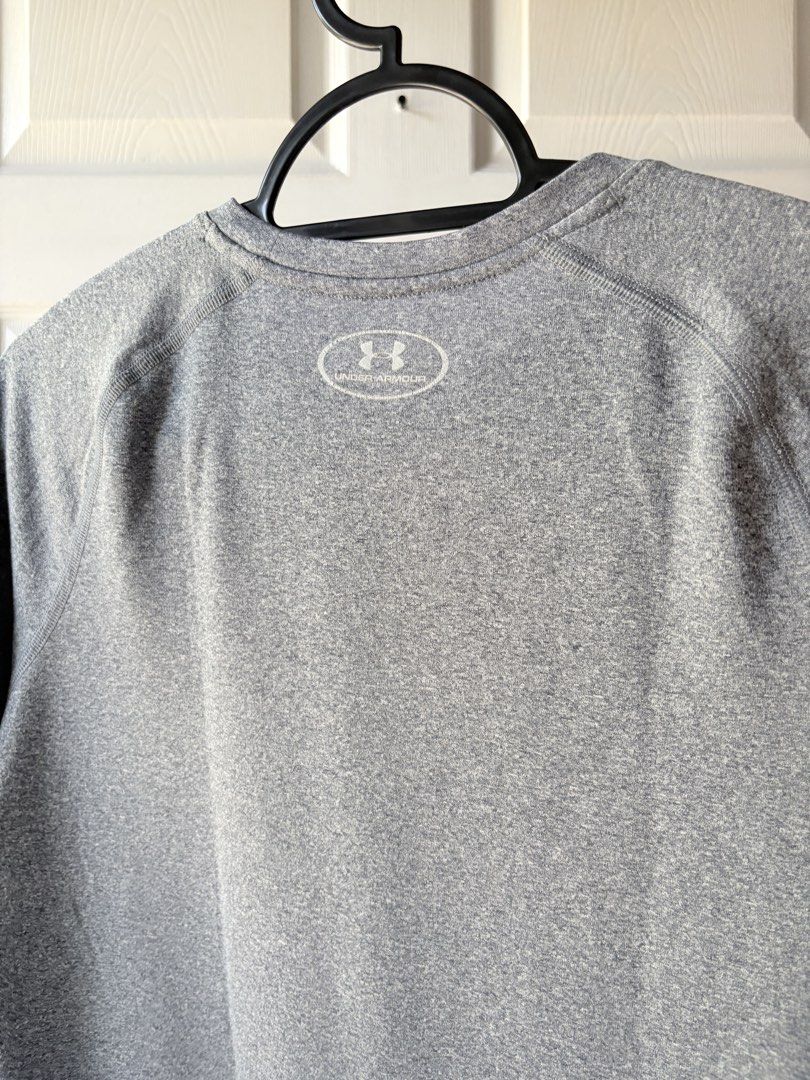 Under Armour Grey Athletic T-Shirt (Category: Babies & Kids Fashion) located in Liloan. Submitted by mrs.jboiser (Listing ID 1469202892, Image 3). Description: - Brand: Under Armour - Color: Grey with silver reflective logos (chest and back collar) - Style: Short sleeves, crew neck, raglan seams - Material: Lightweight, breathable athletic fabric - Condition: Excellent / Pre-loved.