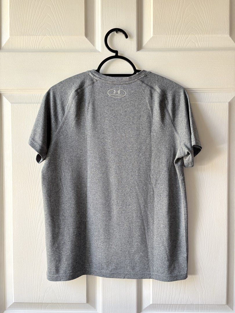 Under Armour Grey Athletic T-Shirt (Category: Babies & Kids Fashion) located in Liloan. Submitted by mrs.jboiser (Listing ID 1469202892, Image 2). Description: - Brand: Under Armour - Color: Grey with silver reflective logos (chest and back collar) - Style: Short sleeves, crew neck, raglan seams - Material: Lightweight, breathable athletic fabric - Condition: Excellent / Pre-loved.