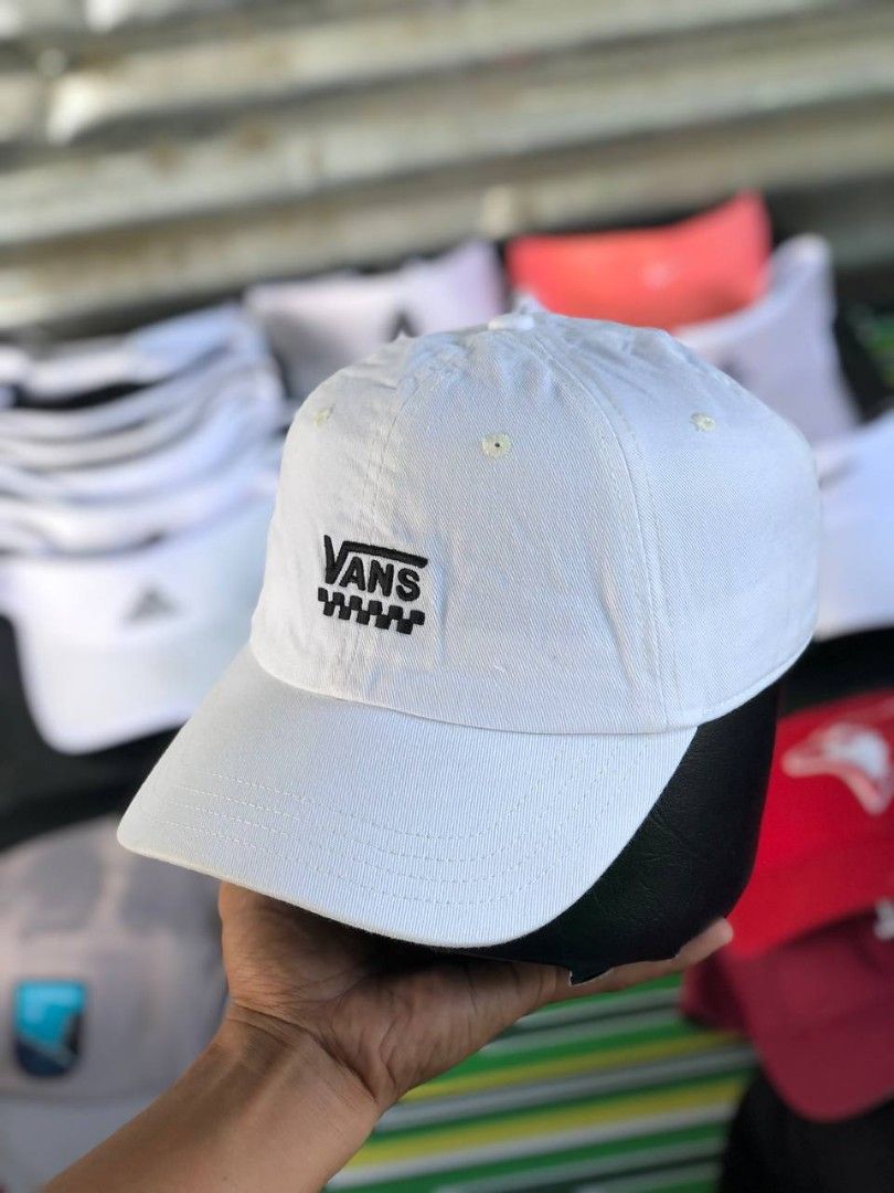 Vans White Baseball Cap with Checkerboard Logo (Category: Caps & Hats) located in Manila. Submitted by jowiegarci63146 (Listing ID 1469311228, Image 2). Description: - Color: Clean white - Design: Embroidered Vans text with stylish checkerboard pattern detail - Fit: Adjustable strap closure at the back with a branded metal buckle - Features: Curved brim, breathable eyelets, and small woven Vans label - Style: Versatile streetwear piece perfect fo