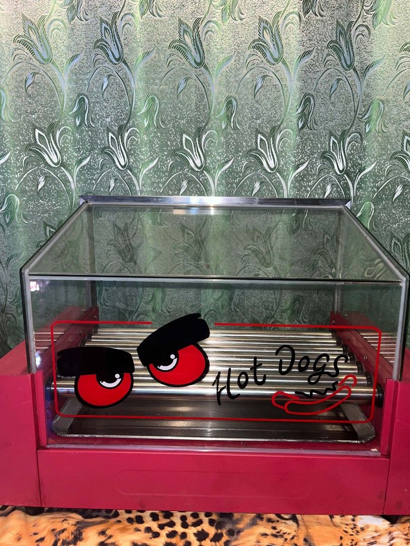 Verly 7 Pin Hotdog Roller Grill Machine (Category: BBQ, Grills & Hotpots) located in Manila. Submitted by iamgraceco16493 (Listing ID 1469164156, Image 3). Description: - 7 heavy-duty stainless steel rollers for even cooking - Eye-catching red base with clear glass display cover - Front temperature control knobs for easy heat management - Dual power switches with handy indicator lights - Fun 'Hot Dogs' graphic decal on the glass - Ideal for conve