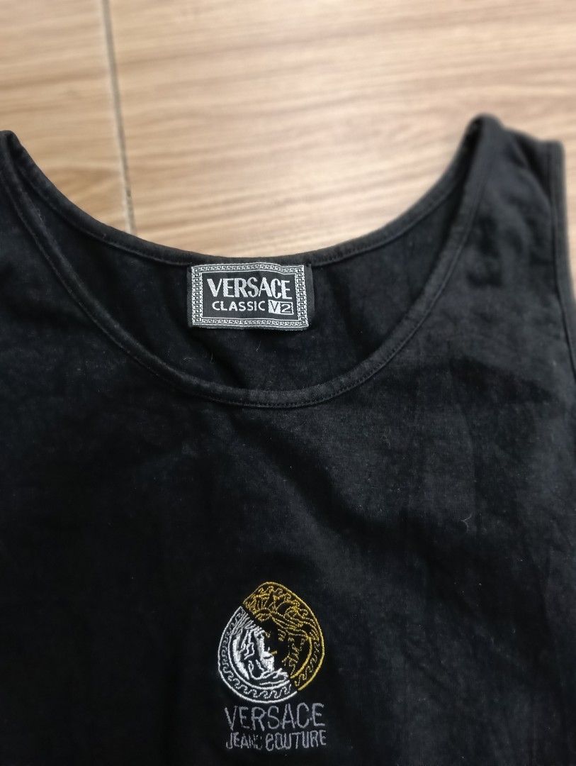 Versace Classic V2 Black Tank Top (Category: Sleeveless) located in Zamboanga. Submitted by nurjim_hajim (Listing ID 1469211982, Image 2). Description: - Brand: Versace Classic V2 - Color: Black - Material: 95% Cotton - Design: Gold and silver embroidered Versace Jeans Couture circular crest logo on the front - Fit: Classic fit - Condition: Clean piece with clear branding.