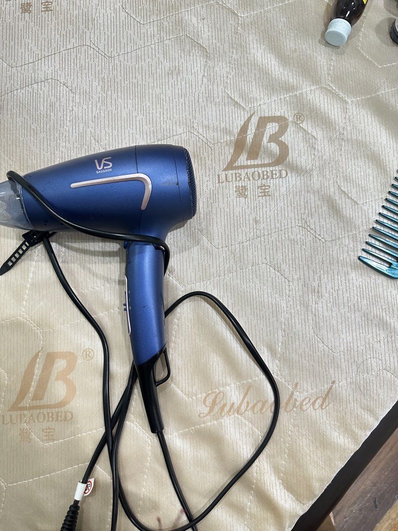Vidal Sassoon Blue Hair Dryer (Category: Hair) located in San Juan City. Submitted by rose.lucky (Listing ID 1469202122, Image 2). Description: - Brand: Vidal Sassoon - Color: Blue - Condition: Working great, ideal for daily styling - Features: Standard handle design with convenient side control switches - Convenience: Built-in cord and plug for easy use and storage - Inclusion: Comes with a nozzle attachment.
