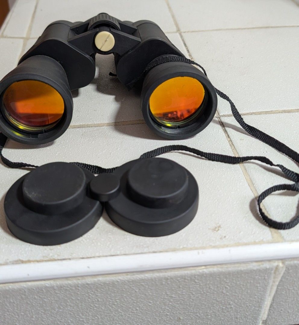 Vintage binoculars (Category: Travel Essentials & Accessories) located in Manila. Submitted by kikopabilla (Listing ID 1469173418, Image 1). Description: The image shows a pair of black porro prism binoculars with ruby/amber-coated objective lenses, accompanied by protective rubber lens caps..