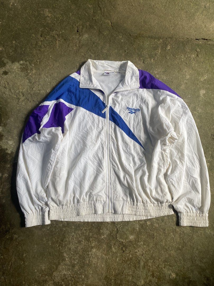 vintage rare reebok windbreaker large (Category: Coats, Jackets and Outerwear) located in Caloocan City. Submitted by remythrift (Listing ID 1469202027, Image 1). Description: - Brand: Reebok - Type: Vintage Rare Windbreaker - Size: Large (L) - Color: White with blue and purple accents - Material: Lightweight nylon with breathable mesh inner lining - Features: Embroidered chest logo, full zip with branded puller, elastic hem and cuffs - Condition