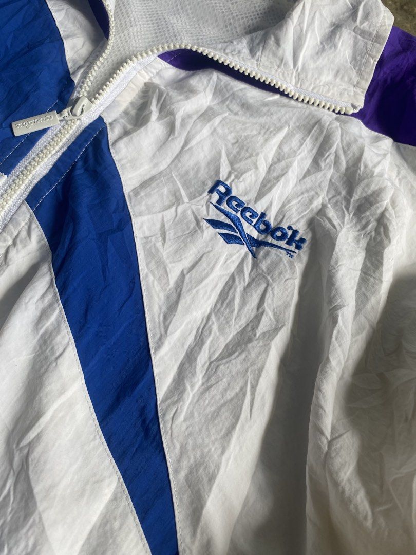 vintage rare reebok windbreaker large (Category: Coats, Jackets and Outerwear) located in Caloocan City. Submitted by remythrift (Listing ID 1469202027, Image 2). Description: - Brand: Reebok - Type: Vintage Rare Windbreaker - Size: Large (L) - Color: White with blue and purple accents - Material: Lightweight nylon with breathable mesh inner lining - Features: Embroidered chest logo, full zip with branded puller, elastic hem and cuffs - Condition