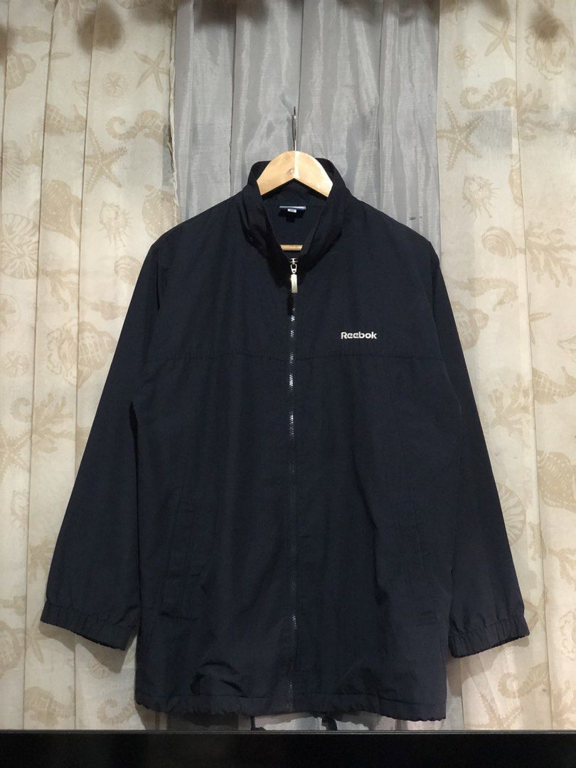 Vintage Reebok Navy Windbreaker Jacket (Category: Coats, Jackets and Outerwear) located in Calbayog City. Submitted by thriftme.bro (Listing ID 1469324471, Image 1). Description: Navy blue Reebok windbreaker in size 105. Features a full zip, high neck, and embroidered logos on the chest and sleeve. Lightweight and easy to layer..