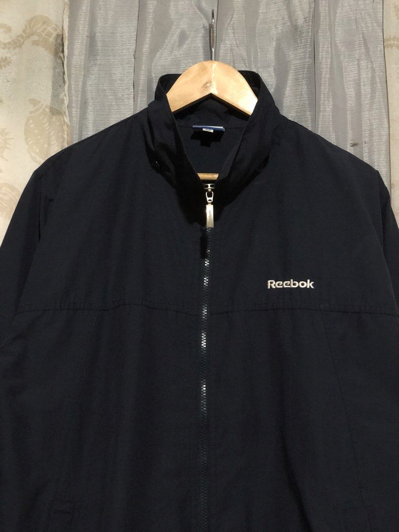 Vintage Reebok Navy Windbreaker Jacket (Category: Coats, Jackets and Outerwear) located in Calbayog City. Submitted by thriftme.bro (Listing ID 1469324471, Image 2). Description: Navy blue Reebok windbreaker in size 105. Features a full zip, high neck, and embroidered logos on the chest and sleeve. Lightweight and easy to layer..