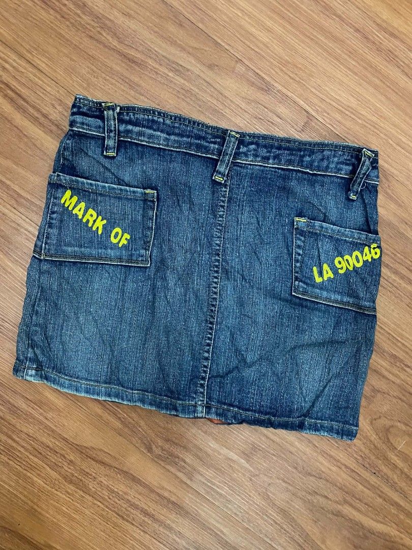 Von Dutch Denim Skirt Size S Y2K (Category: Skirts) located in Malasiqui. Submitted by finnley26 (Listing ID 1469232821, Image 3). Description: - Brand: Von Dutch - Size: 30 LENGTH: 14 - Wash: Dark wash blue denim - Design: Bold orange Von Dutch logo on front, yellow car graphic on pocket, and yellow text prints on back pockets - Hardware: Double-button closure with branded hardware - Style: Classic Y2K streetwear vibe - Condition: Excellent pre-