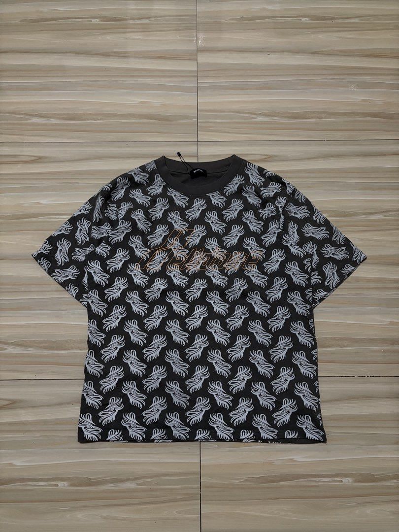 We11done All-Over Print T-Shirt Size M (Category: Tshirts & Polo Shirts ) located in Ajuy. Submitted by reeyn0515 (Listing ID 1469326090, Image 1). Description: - 20.5x26.5 - Brand: We11done - Color: Dark grey with striking tribal-style graphic print - Size: Medium (M) - Details: Contrast orange embroidered logo on chest, classic crew neck - Authenticity: Includes original neck tags, interior care tags with batch code WD-TP6-20-074-U-3K, and auth