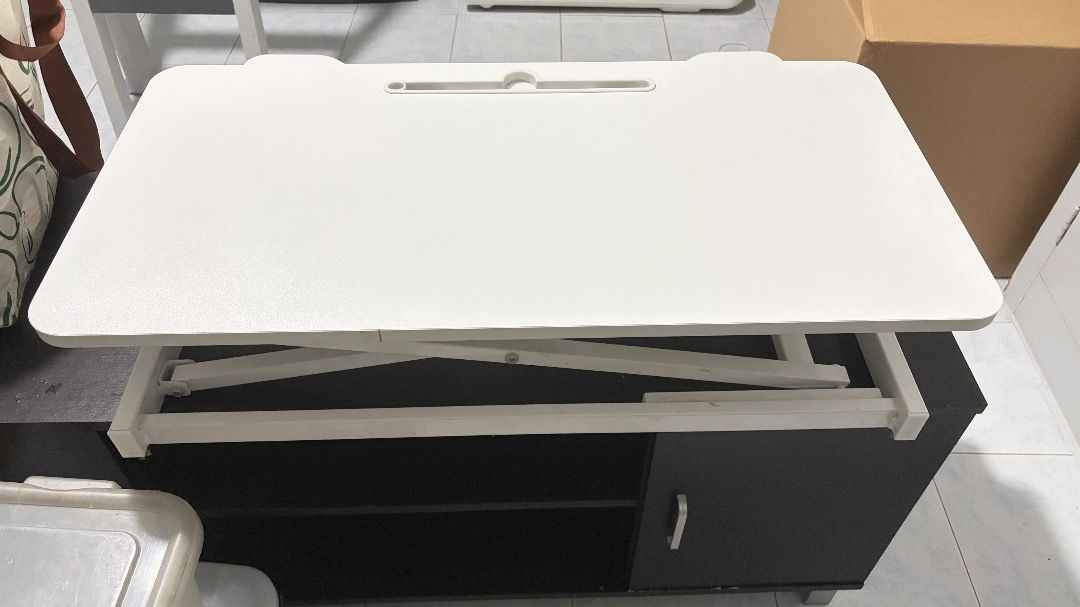 White adjustable desk/table riser (Category: Office Furniture & Fixtures) located in Quezon City. Submitted by roseyfinds (Listing ID 1469217031, Image 3). Description: Move-out sale. White 2-level desktop riser Looks good as new. Pick-up only via Lalamove or by buyer..