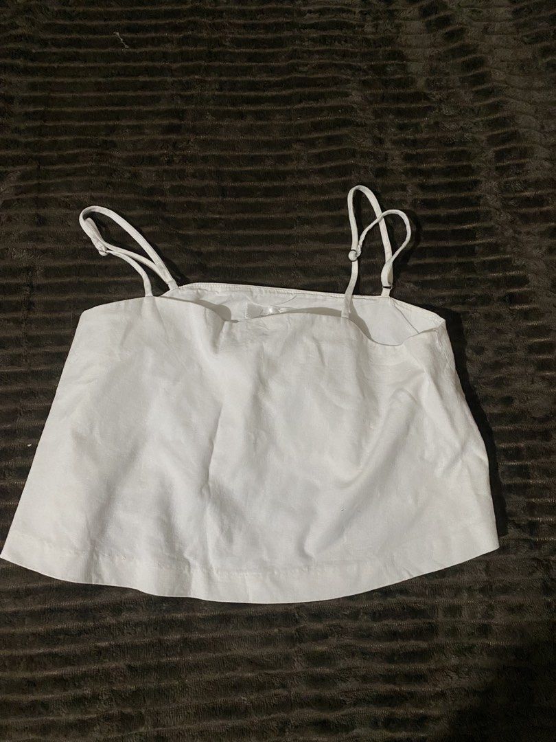 White crop cami top with adjustable straps (Category: Sleeveless) located in Iloilo. Submitted by luckyeagle_1c5618 (Listing ID 1469296008, Image 1). Description: - Color: White - Style: Simple crop top with flowy fit - Straps: Thin spaghetti straps with adjustable buckles - Neckline: Straight neckline with a tiny center bow detail - Material: Clean, neutral fabric that matches everything - Fit: Pull-on style, great for warm weather or layering.