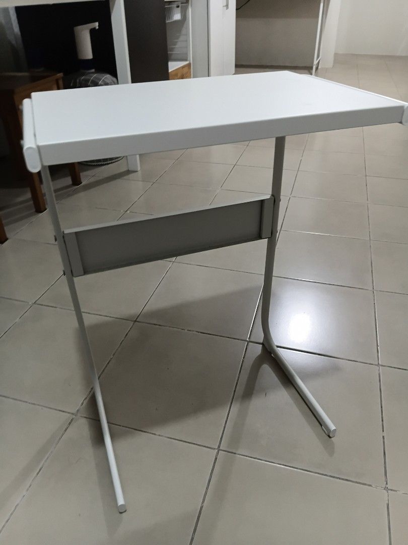 White Metal Laptop Stand Desk Riser (Category: Office Furniture & Fixtures) located in Makati City. Submitted by mkdmaniego (Listing ID 1469241563, Image 2). Description: - Color: Clean white finish that matches any room setup - Material: Sturdy curved metal tube frame for desk stability - Extra Storage: Includes a small middle shelf for pens, a notebook, or small accessories - Compatibility: Standard size fits most laptops and small monitors kin