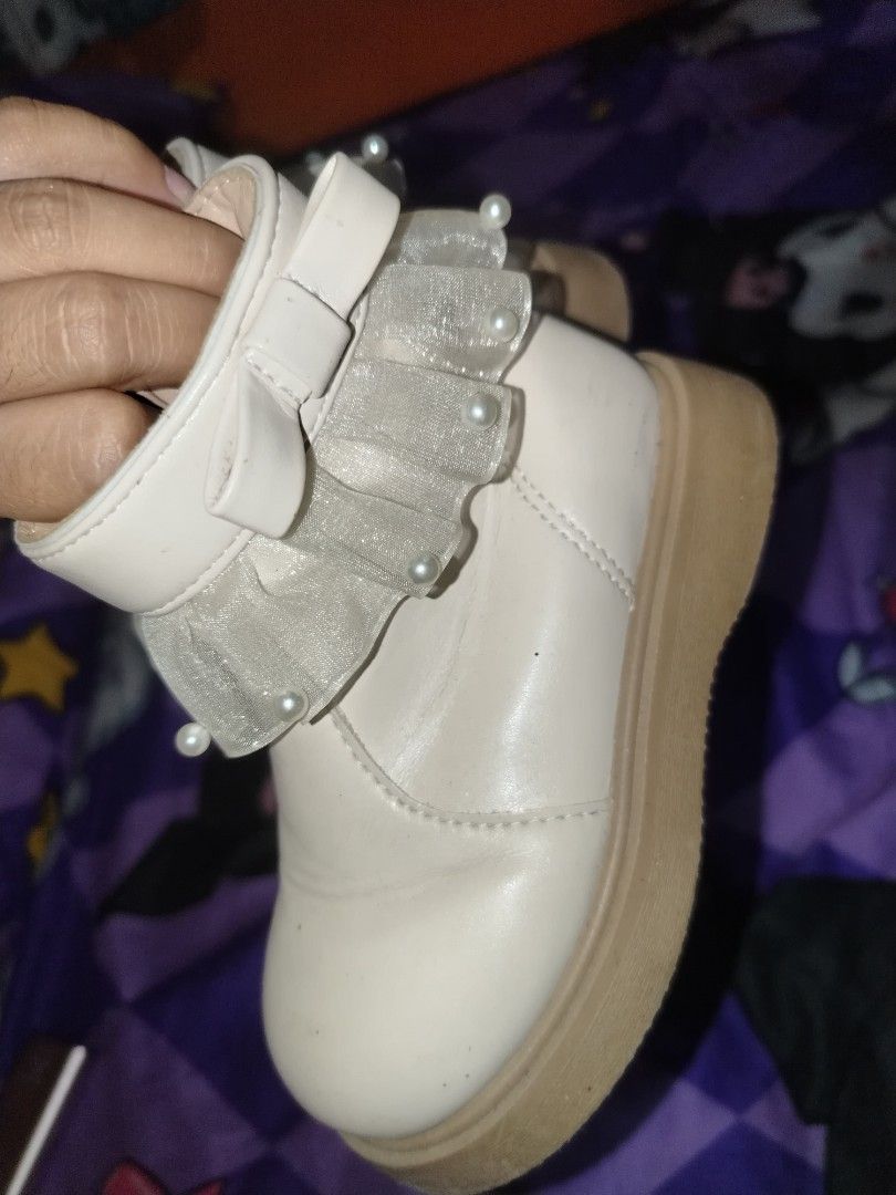 White pearl ruffle girls boots (Category: Babies & Kids Fashion) located in Manila. Submitted by nesacake (Listing ID 1469295906, Image 1). Description: - Style: White ankle boots with cute side bow, pearl trim, and sheer ruffles - Sole & Closure: Chunky brown sole with convenient side zipper for easy wear - Condition: Clean overall with minor scuffs on the toe area - Perfect for adding a sweet, feminine touch to your outfit!.