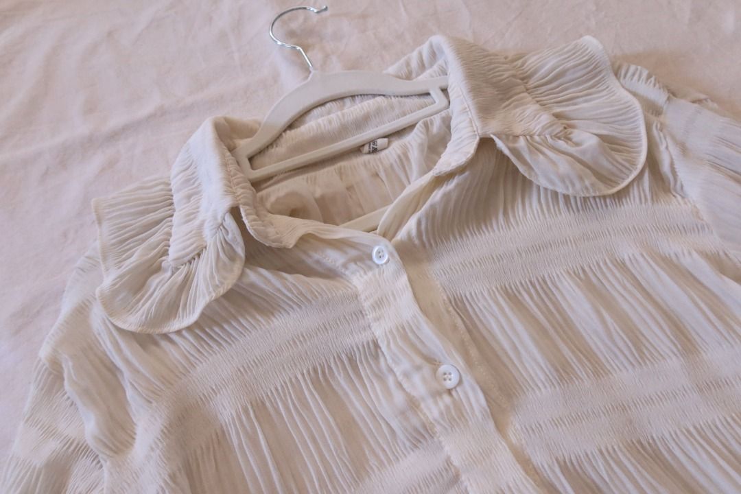 White Ruffle Collar Button-Down Blouse Long Sleeve (Category: Blouses) located in Manila. Submitted by imama23 (Listing ID 1469197311, Image 2). Description: - Color: White - Style: Vintage-inspired button-down blouse with textured pleated panels - Details: Large statement ruffle collar, flared cuffs, and front button closure - Fabric: Lightweight and slightly sheer Condition: 8/10 Size: M-L Location: Manila (near taft) 📦 SHIPPING • Full payment