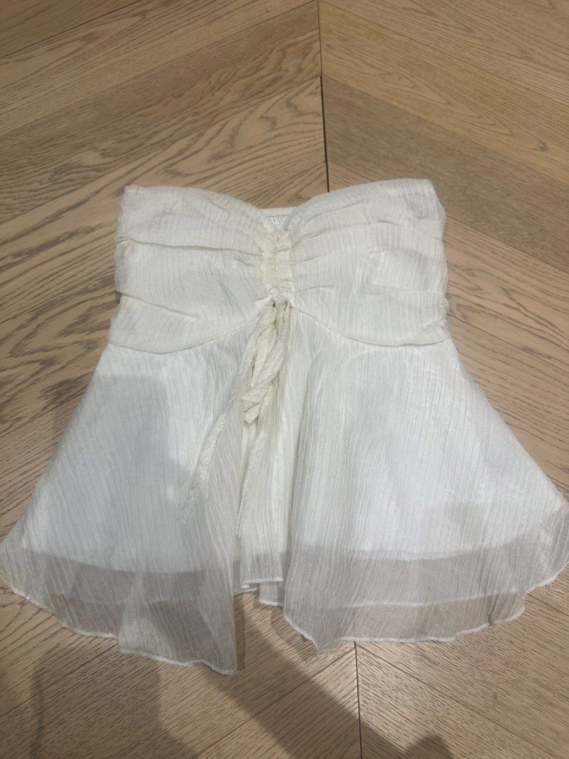 White tube top (Category: Sleeveless) located in Quezon City. Submitted by 49diam (Listing ID 1469287410, Image 1). Description: - Color: White - Style: Strapless tube top with ruched center and adjustable front tie - Design: Flowy pleated fabric with a sheer layered hem - Material: Lightweight and breathable, ideal for warm weather - Versatility: Easy to style with high-waisted jeans or skirts.