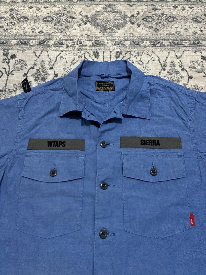 Wtaps Japan Buds 01 Chambray Shirt (Category: Activewear) located in Quezon City. Submitted by selling2survive (Listing ID 1469175190, Image 2). Description: Military-inspired fatigue build with dual button-down chest pockets, contrasting “WTAPS” and “SIERRA” name patches, branded buttons, and a woven red brand tag on the pocket Length: 27 Pit to pit: 21 Shoulder: 17 No issue .