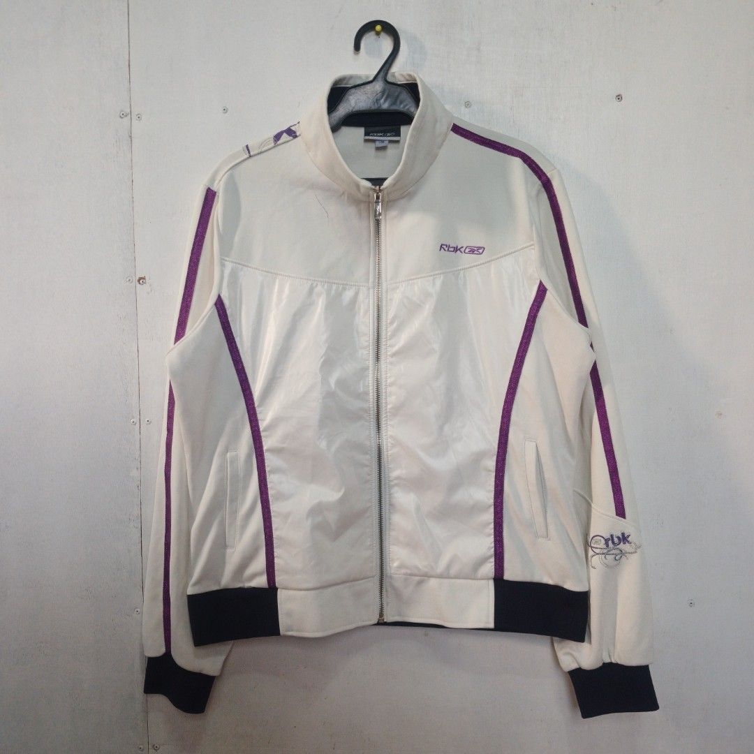 Y2K-era Reebok track jacket (Category: Coats, Jackets and Outerwear) located in Manila. Submitted by joefrey12 (Listing ID 1469238622, Image 1). Description: - Authentic white Reebok track jacket - Dimes 21x24.5 - Eye-catching purple glitter piping on sleeves and chest - Contrast dark navy cuffs and collar trim - Purple RBK embroidered logo on right chest with fancy silver-stitched RBK embroidery near the left shoulder - Full front zip closure wi