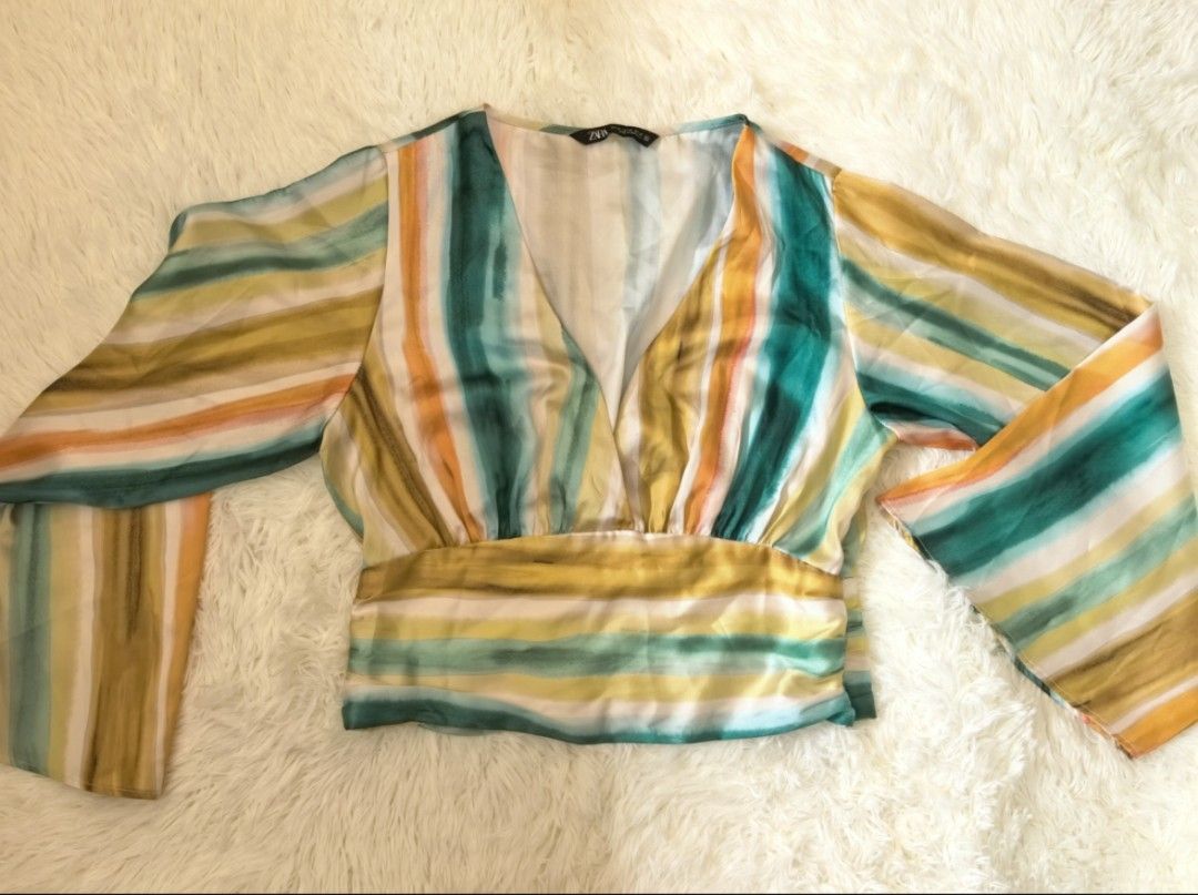 Zara Striped V-Neck Wrap Blouse Size M (Category: Blouses) located in Tacloban City. Submitted by thead.declutters (Listing ID 1469217988, Image 1). Description: - Brand: Zara - Style: Wrap blouse with deep V-neck and banded waist - Pattern: Multi-color watercolor vertical stripes (teal, yellow, orange, white) - Size: Medium (Pit-to-pit: ~14" flat lay) - Material: Lightweight silky fabric - Condition: Excellent pre-loved condition - Perfect for: 