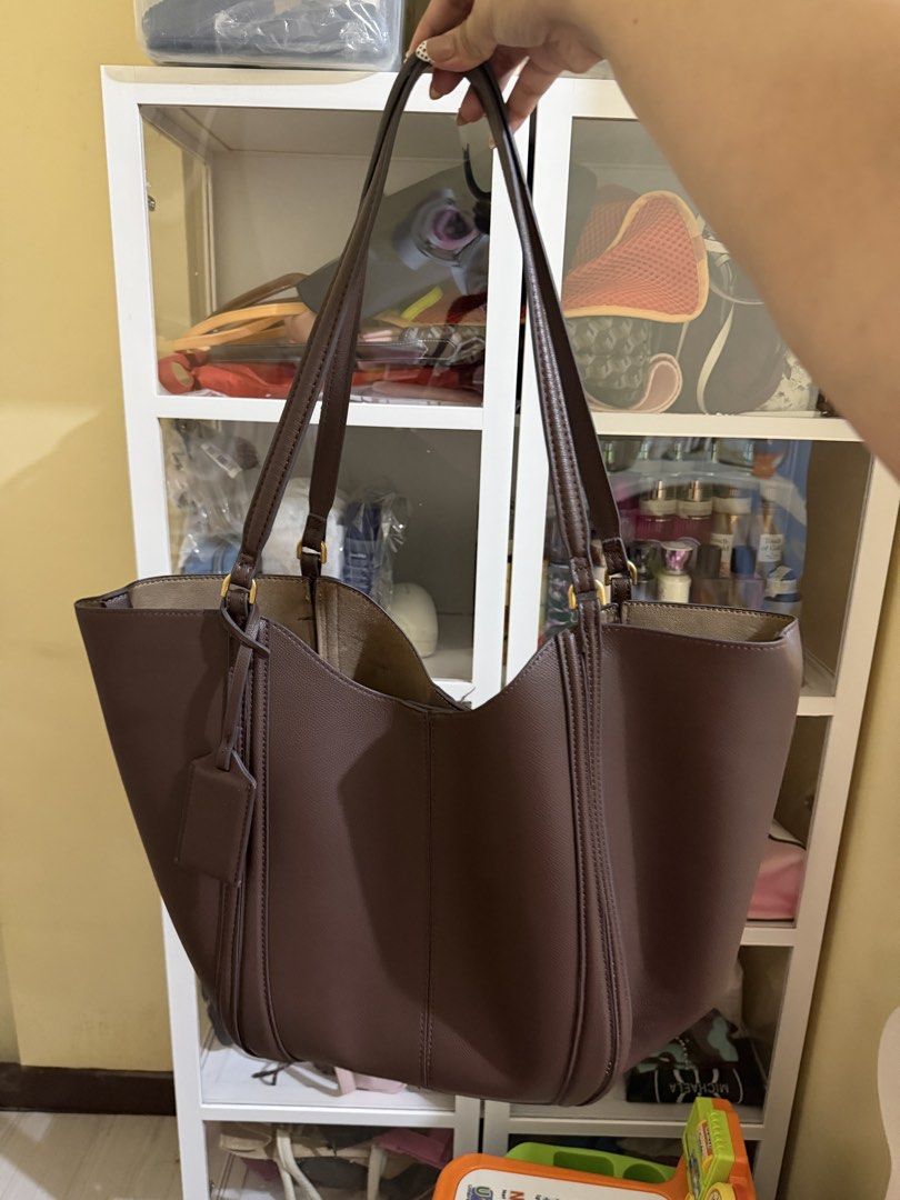 ZARA TOTE BAG (Category: Tote Bags) located in Makati City. Submitted by beymadrigal (Listing ID 1469232824, Image 2). Description: - Color: Dark brown - Style: Structured tote bag with dual shoulder straps - Closure: Snap button top closure - Interior: Roomy with a middle zipper compartment for organization and clean lining - Extras: Includes a matching luggage tag charm - Ideal for: Everyday use for work or school.