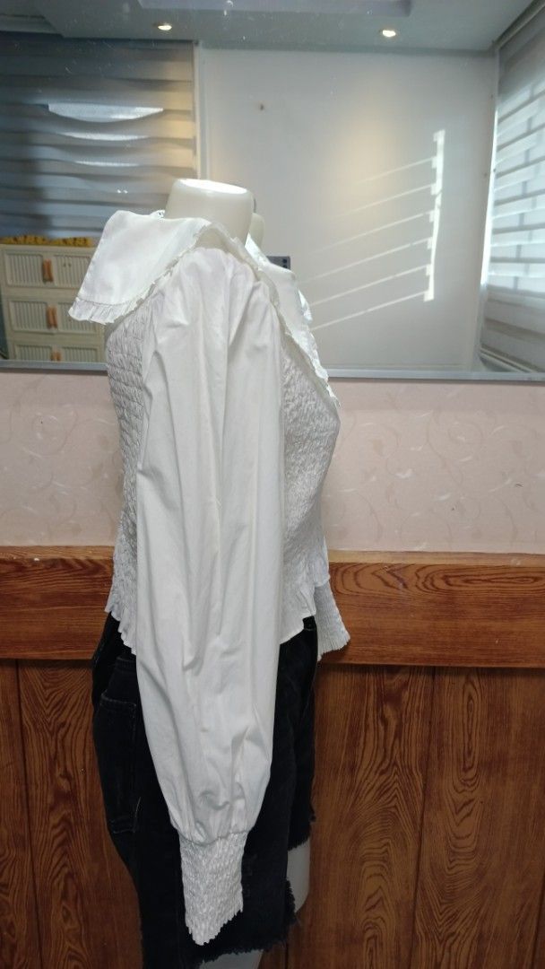 ZARA White Blouse with Oversized Ruffle Collar (Category: Blouses) located in General Santos City (Dadiangas). Submitted by amzonshop (Listing ID 1469239348, Image 3). Description: - Color: White - Design: Wide ruffle collar and smocked body - Sleeves: Long sleeves with ruffled cuffs - Closure: Back zipper - Styling: Great to pair with denim shorts or skirts for a casual look .