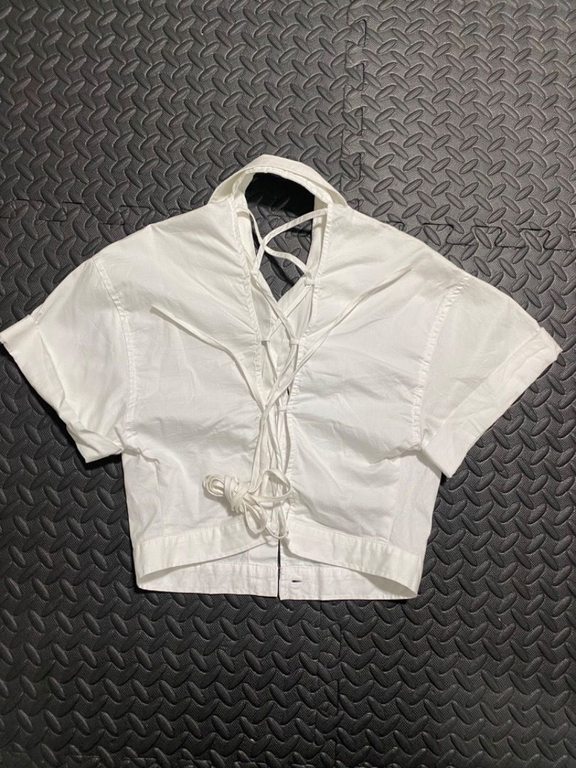 Zara White Cropped Button-Up Shirt (Category: Shirts) located in Manila. Submitted by everydrei (Listing ID 1469203968, Image 2). Description: - Brand: Zara - Color: White - Material: Structured cotton - Style: Crop top with short sleeves (folded cuffs), standard collar, and button-down front - Special Detail: Unique criss-cross strap design at the back neckline - Fit: True to size, looks great with high-waisted bottoms.