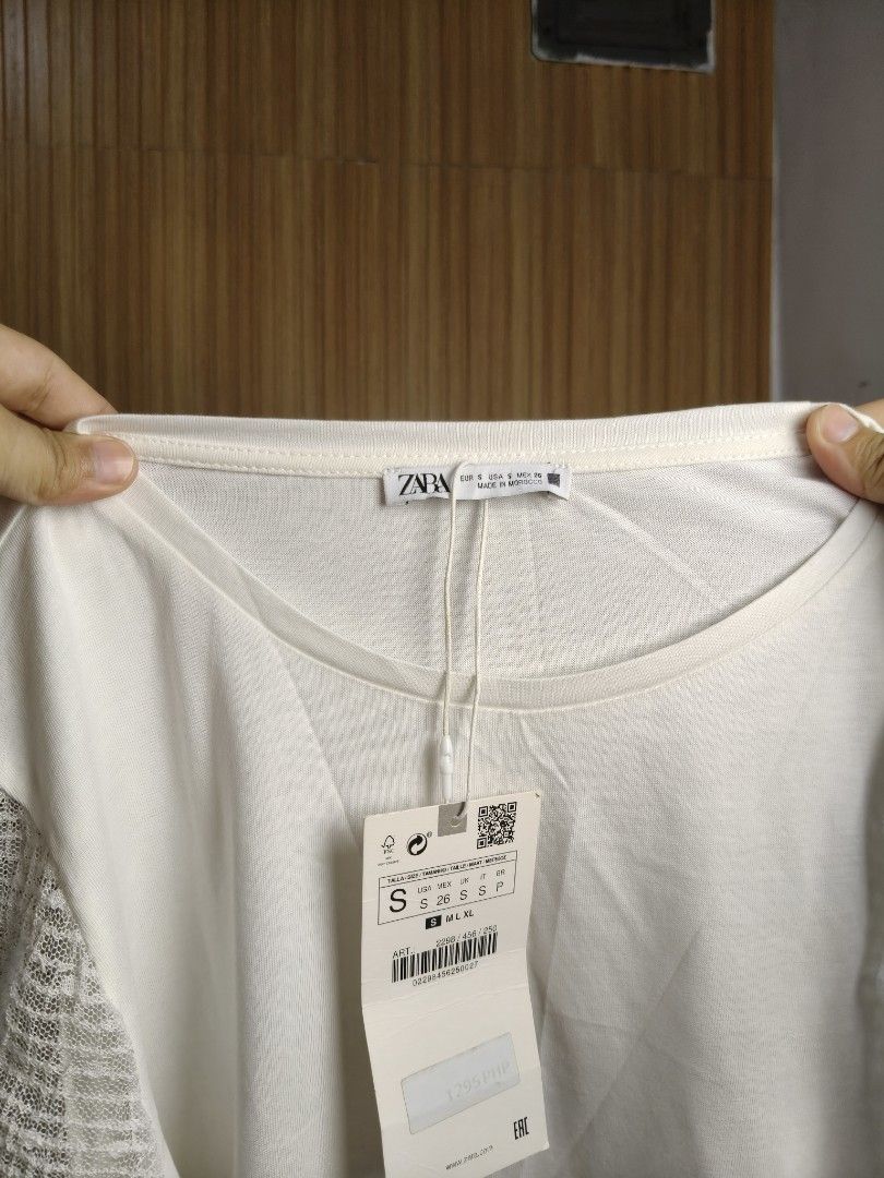 Zara White Top with Sheer Sleeves (Category: Shirts) located in Taguig. Submitted by ashie_clothing (Listing ID 1469205242, Image 3). Description: - Brand: Zara - Condition: Brand new with tags (BNWT) - Size: S - Color: Crisp white - Material: Lightweight with textured details - Features: Short lace sleeves, crew neckline, regular fit - Origin: Made in Morocco - Styling: Easy to match with denim or skirts.