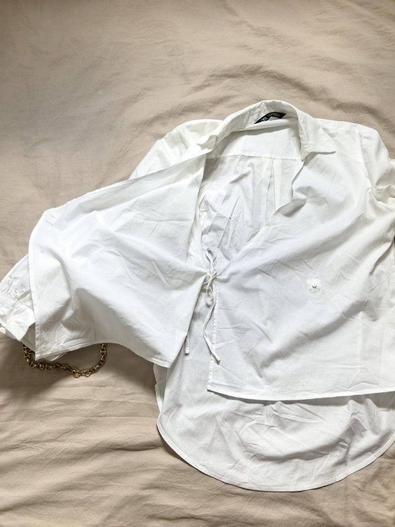 ZARA White Wrap Shirt Size XS (Category: Blouses) located in Tacloban City. Submitted by thead.declutters (Listing ID 1469217989, Image 2). Description: - Brand: ZARA - Color: Classic White - Size: EUR XS / US XS / MEX 24 - Design: Asymmetric wrap front with stylish tie closures - Details: Long sleeves with cuffed wrists and high-low curved hemline - Origin: Made in Indonesia - Condition: Clean, minimal look - Styling: Highly versatile; easily pa