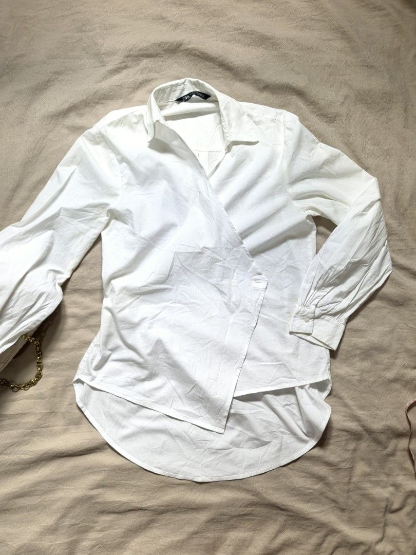 ZARA White Wrap Shirt Size XS (Category: Blouses) located in Tacloban City. Submitted by thead.declutters (Listing ID 1469217989, Image 1). Description: - Brand: ZARA - Color: Classic White - Size: EUR XS / US XS / MEX 24 - Design: Asymmetric wrap front with stylish tie closures - Details: Long sleeves with cuffed wrists and high-low curved hemline - Origin: Made in Indonesia - Condition: Clean, minimal look - Styling: Highly versatile; easily pa