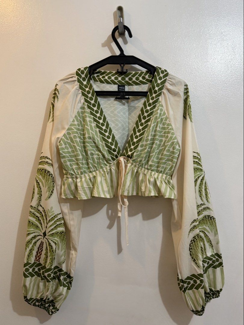 10PCS SHEIN COORDS (Category: Sleeveless) located in Mandaluyong City. Submitted by deanescloset (Listing ID 1469511578, Image 3). Description: - Brand: Shein - Design: Green and white palm tree print - Neckline: V-neck with front tie string - Sleeves: Long balloon sleeves with patterned cuffs - Fit: Crop top, short length cut - Material: Soft and comfortable fabric - Ideal for: Warm weather, beach trips, and vacations.
