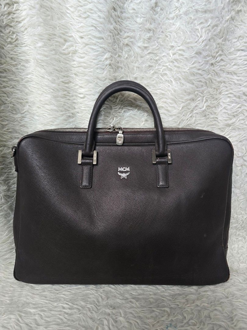 💯% AUTHENTIC MCM Dark Brown Leather Business Briefcase Bag (Category: Luxury Bags & Wallets) located in Marikina City. Submitted by dust.end.bags (Listing ID 1469567619, Image 1). Description: - Brand: MCM - Material: Premium dark brown textured leather - Hardware: Silver-tone with front stamped MCM logo - Closure: Secure top and side zip closure - Handles: Dual structured top handles - Design: Professional workspace bag with a flat base for eas