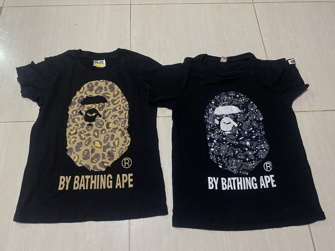 A Bathing Ape BAPE By Bathing Ape T-Shirts (Category: Activewear) located in Alburquerque. Submitted by zanegavynn43872 (Listing ID 1469490003, Image 1). Description: (Bundle of 2) - Designs: 1) Yellow leopard camo ape head with gold lettering, 2) Dark starry night galaxy camo ape head with white lettering - Material: Premium soft cotton - Details: Classic collar tags and sleeve ape tags fully intact - Style: Streetwear staples, .