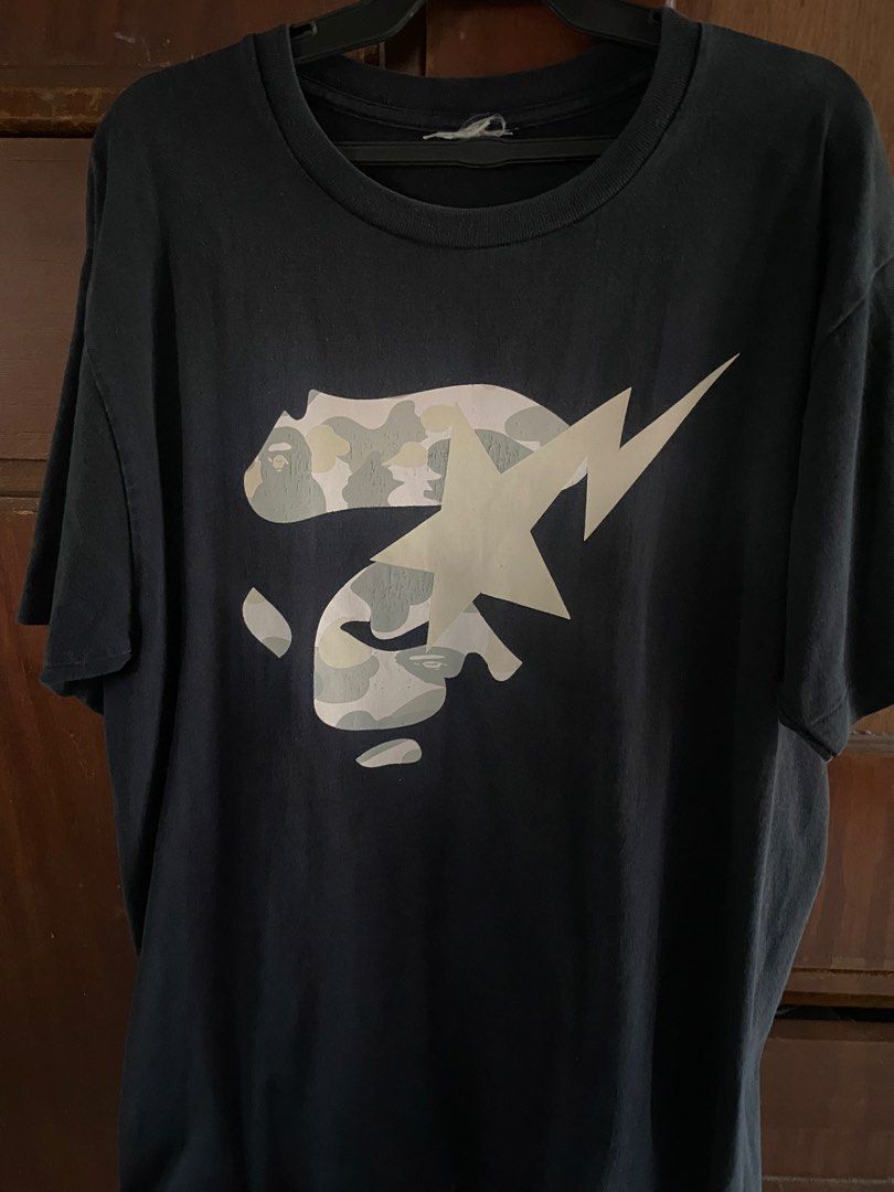 A Bathing Ape Bape Camo Sta T-Shirt (Category: Tshirts & Polo Shirts ) located in Manila. Submitted by upcycleutopia_ (Listing ID 1469477428, Image 1). Description: - Brand: A Bathing Ape (BAPE) - Color: Black - Size: medium - Design: medium chest graphic with camo Bape head, lightning bolt sta, and bottom hem branding - Details: Small embroidered ape logo tag on sleeve cuff, classic crew neck, short sleeves - Condition: Pre-owned with some natur
