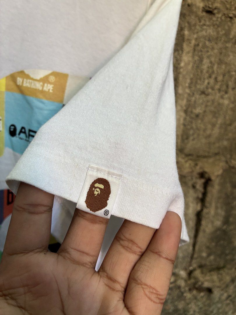 A Bathing Ape BAPE Multi Graphic Tee White (Category: Tshirts & Polo Shirts ) located in Manila. Submitted by assortedgoodsv3 (Listing ID 1469463655, Image 3). Description: - Brand: A Bathing Ape (BAPE) - Color: White - Size: Large - Material: 100% Cotton, Made in Japan - Design: Large multi-graphic ape head silhouette print with logo patches - Authenticity details: Classic collar tag and sleeve ape head tag included - Condition: Excellent / Well