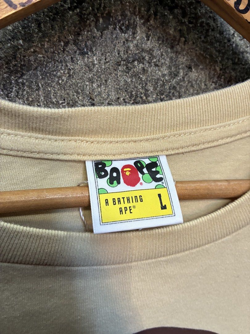 A Bathing Ape Bape Tee Yellow Large (Category: Tshirts & Polo Shirts ) located in Manila. Submitted by assortedgoodsv3 (Listing ID 1469463334, Image 3). Description: - Brand: Bape - Item: Short sleeve tee - Color: Light yellow - Size: L (Large) - Material: 100% cotton, made in China - Design: Large ape head graphic on chest, matching back graphic, and small sleeve tag - Condition: Clean with clear, crack-free prints.