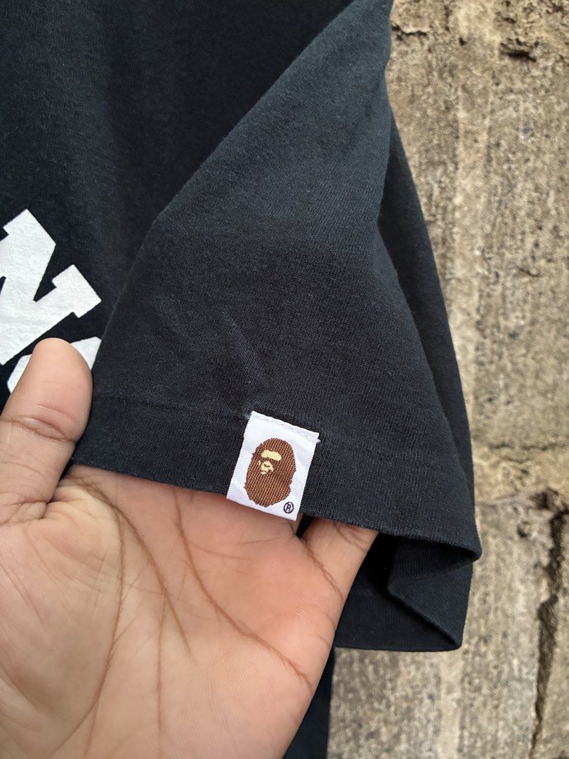 A Bathing Ape Black T-Shirt with Blue Camo (Category: Tshirts & Polo Shirts ) located in Manila. Submitted by assortedgoodsv3 (Listing ID 1469463515, Image 3). Description: ISSUE CUT MAIN TAG BUT AUTHENTIC,MONEY BACK IF FAKE - Brand: A Bathing Ape (BAPE) - Color: Black - Size: Large - Design: Large chest graphic with white lettering and iconic blue camo ape head logo - Details: Classic crew neck, short sleeves, and signature embroidered ape head 