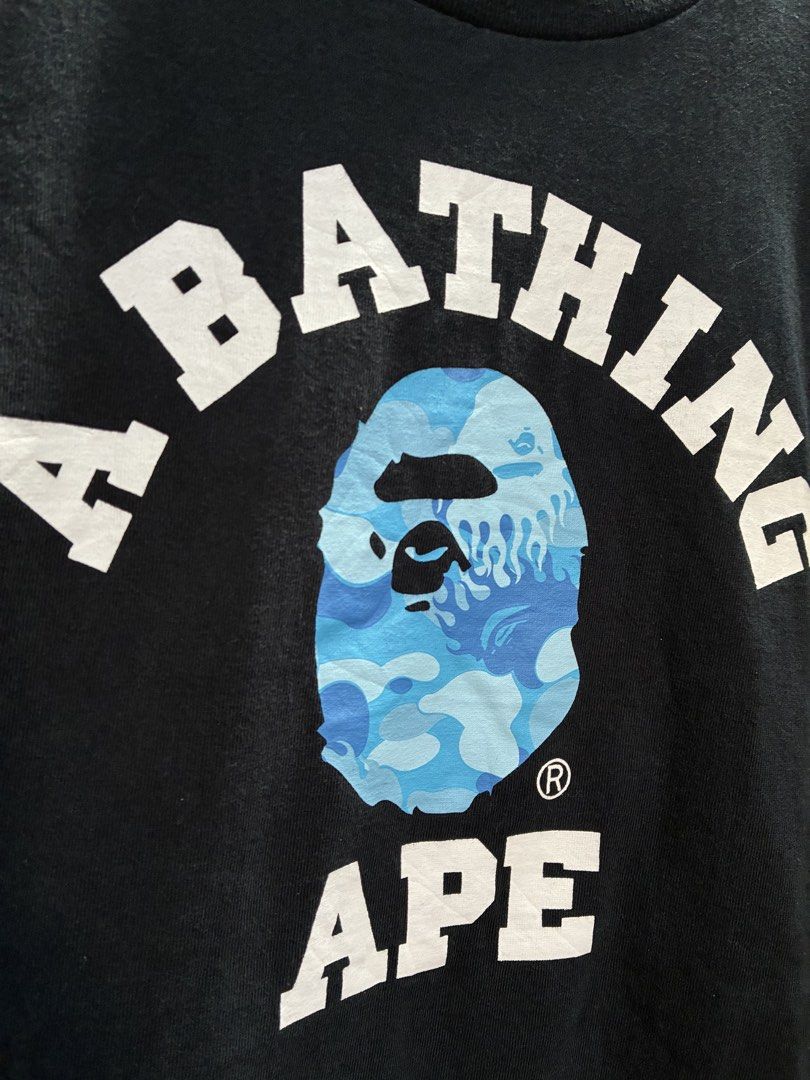 A Bathing Ape Black T-Shirt with Blue Camo (Category: Tshirts & Polo Shirts ) located in Manila. Submitted by assortedgoodsv3 (Listing ID 1469463515, Image 2). Description: ISSUE CUT MAIN TAG BUT AUTHENTIC,MONEY BACK IF FAKE - Brand: A Bathing Ape (BAPE) - Color: Black - Size: Large - Design: Large chest graphic with white lettering and iconic blue camo ape head logo - Details: Classic crew neck, short sleeves, and signature embroidered ape head 