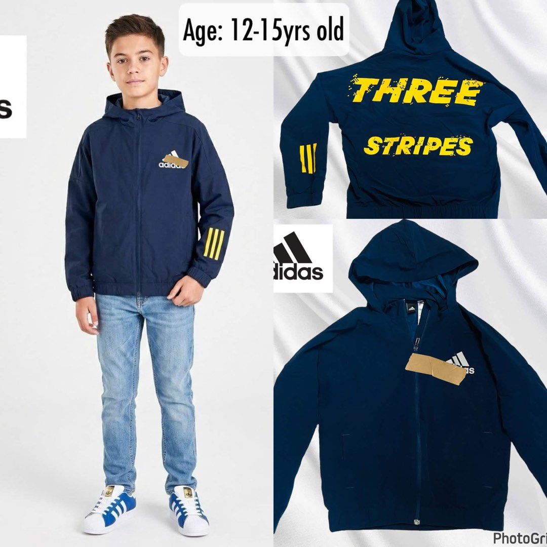 Adidas Kids Hooded Jacket |Size 140 (Category: Babies & Kids Fashion) located in Manila. Submitted by bengirlclothing (Listing ID 1469428890, Image 1). Description: - Brand: Adidas - Size: Tagged Asia 140 (recommended for ages 12-15 years old) - Color: Navy blue with bold yellow and white accents - Design: Full-zip jacket with built-in hood, side pockets, front Adidas logo, yellow sleeve stripes, and 'THREE STRIPES' text on the back - Material: L