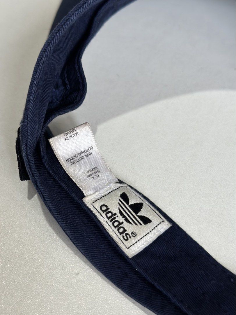 Adidas Navy Blue Sun Visor (Category: Caps & Hats) located in Daet. Submitted by thrifthings2018 (Listing ID 1469466848, Image 2). Description: - Brand: Adidas - Color: Navy blue with white embroidered trefoil logo - Material: 100% cotton - Size: Adjustable velcro strap for a customized fit - Condition: Clean interior tags visible - Ideal for: Sunny days, running, and outdoor activities.