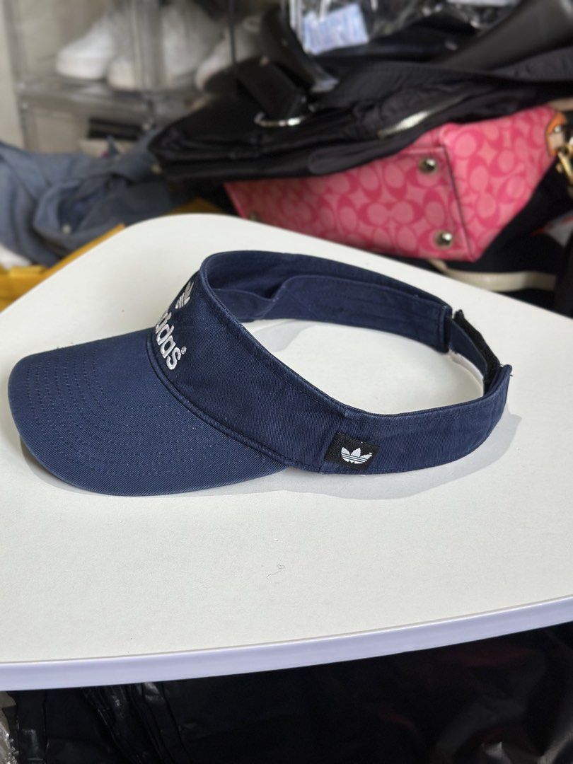 Adidas Navy Blue Sun Visor (Category: Caps & Hats) located in Daet. Submitted by thrifthings2018 (Listing ID 1469466848, Image 3). Description: - Brand: Adidas - Color: Navy blue with white embroidered trefoil logo - Material: 100% cotton - Size: Adjustable velcro strap for a customized fit - Condition: Clean interior tags visible - Ideal for: Sunny days, running, and outdoor activities.