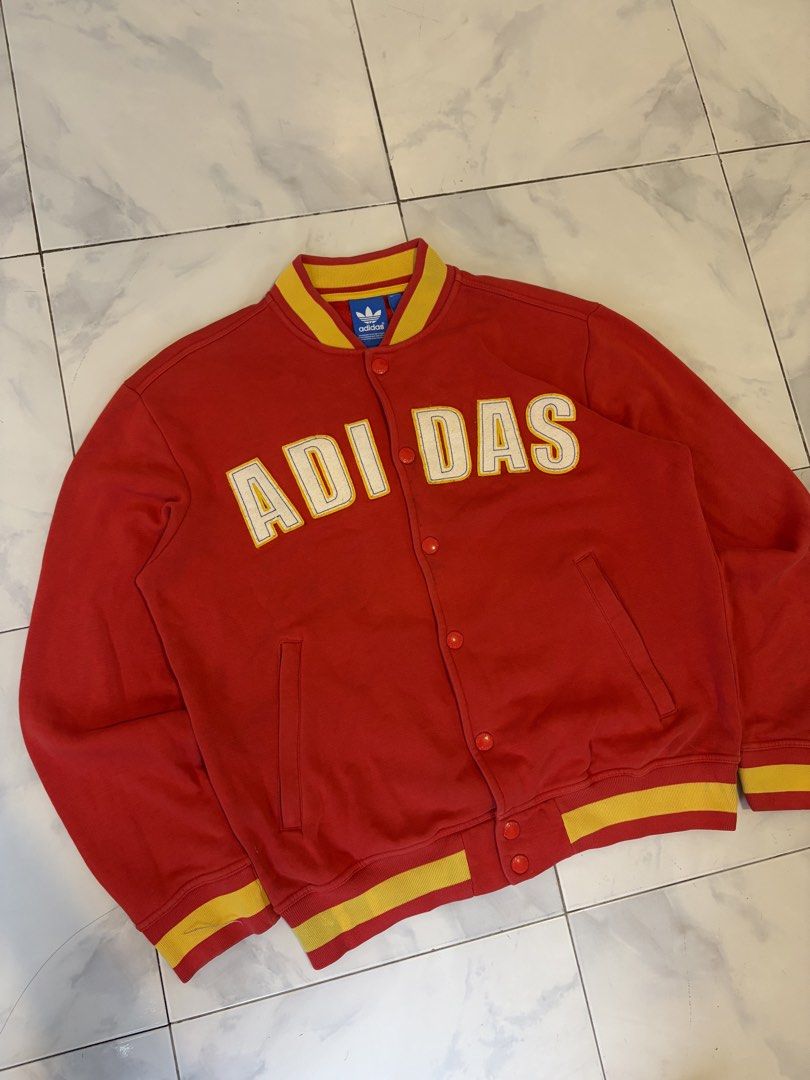 Adidas Red Yellow Varsity Jacket Size M (Category: Coats, Jackets and Outerwear) located in Calauan. Submitted by lancesuerte13 (Listing ID 1469455003, Image 2). Description: - Brand: Adidas - Style: Red varsity jacket with yellow ribbing on collar, cuffs, and hem - Design: Large white and yellow ADIAS lettering patch across the chest - Details: Button-up front closure with branded metal buttons, two front pockets - Authenticity: Features blue tr