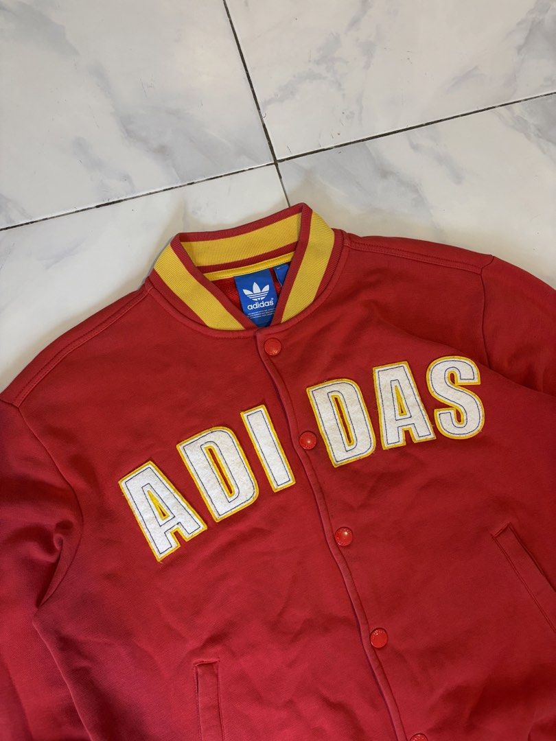 Adidas Red Yellow Varsity Jacket Size M (Category: Coats, Jackets and Outerwear) located in Calauan. Submitted by lancesuerte13 (Listing ID 1469455003, Image 3). Description: - Brand: Adidas - Style: Red varsity jacket with yellow ribbing on collar, cuffs, and hem - Design: Large white and yellow ADIAS lettering patch across the chest - Details: Button-up front closure with branded metal buttons, two front pockets - Authenticity: Features blue tr