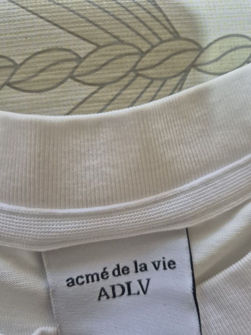 ADLV Bearbrick Graphic White T-Shirt (Category: Shirts) located in Daraga. Submitted by nvdp118255967 (Listing ID 1469456908, Image 2). Description: - Brand: ADLV (Acme de la Vie) - Design: Large Bearbrick art print with colorful graffiti details - Style: Classic crew neck, short sleeves, standard fit - Authenticity: Complete with interior brand labels and wash care tags.