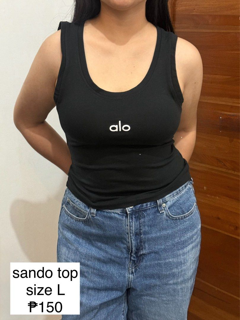 Alo Black Sando Tank Top Size L (Category: Sleeveless) located in Manila. Submitted by sstash444 (Listing ID 1469410599, Image 1). Description: - Brand: Alo - Color: Black with white chest logo - Size: L - Material: Soft, stretchy cotton - Design: Simple scoop neckline - Condition: Clean, excellent, ready to wear - Style: Perfect for easy pairing with jeans or shorts for casual days.