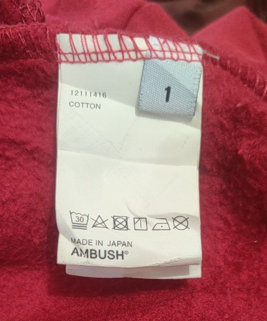 AMBUSH Red Multi-Drawstring Hoodie Size 1 (Category: Hoodies) located in Bago City. Submitted by louielinco (Listing ID 1469437302, Image 3). Description: - Brand: Ambush - Color: Red with white logo text - Size: 1 (Made in Japan) - Material: 100% premium cotton - Details: Distinctive multi-colored braided drawstrings with branded metal aglets and center lock hardware - Features: Standard kangaroo pocket construction - Condition: Interior care ta